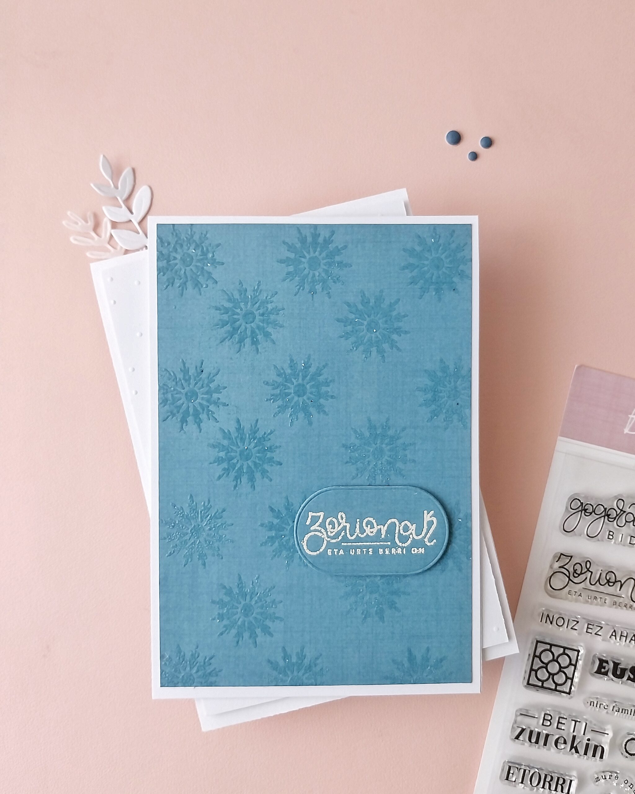 Postal de Navidad hecha con papeles básicos de Mi Calma, troquel Etiquetas y sello Bilbo, en tonos suaves y diseño minimalista.