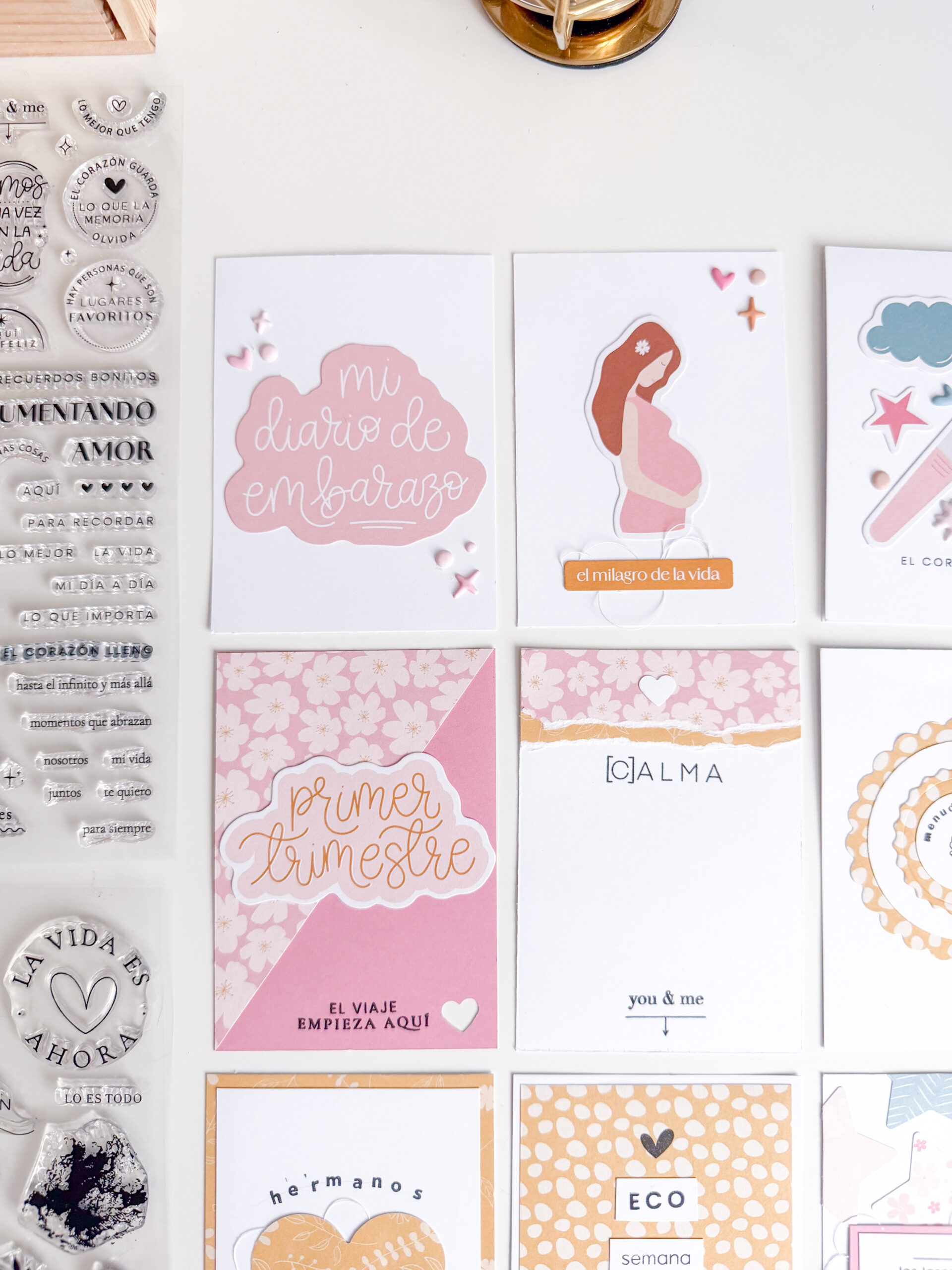     Páginas interiores de un diario de embarazo con tarjetas tipo Project Life, fotografías y papeles decorados.